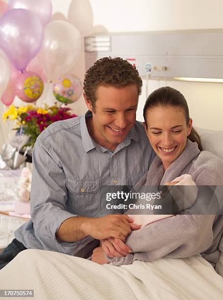 couple holding newborn baby in hospital - baby father hug side stock pictures, royalty-free photos & images