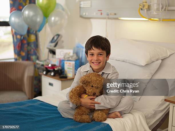 boy sitting in hospital bed with teddy bear - teddy day stockfoto's en -beelden