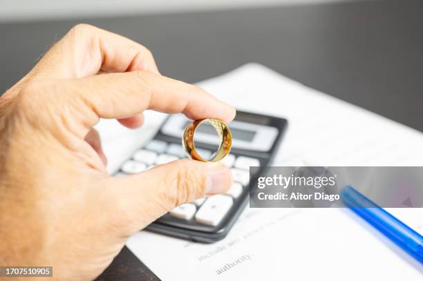 marriage costs (wedding / divorce) a man holds a golden boot wedding ring. on the table is a calculator and a pen. - gold boot stockfoto's en -beelden