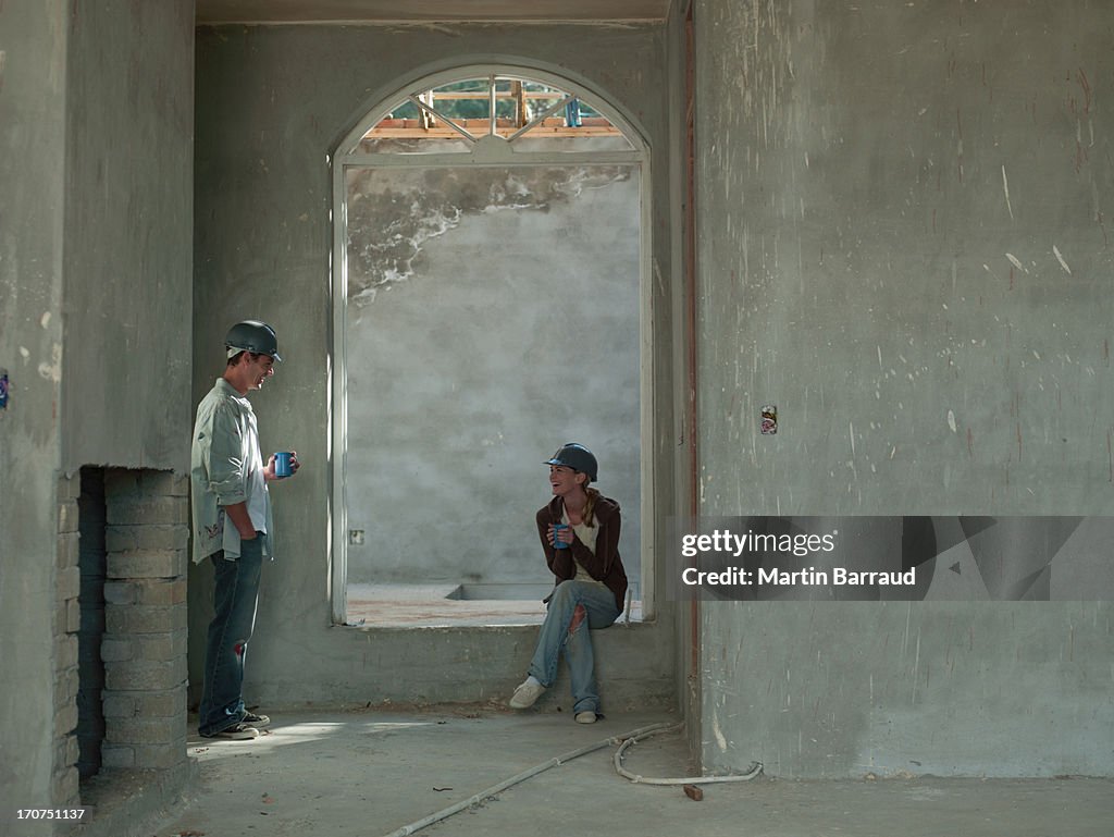Couple drinking coffee in house under construction