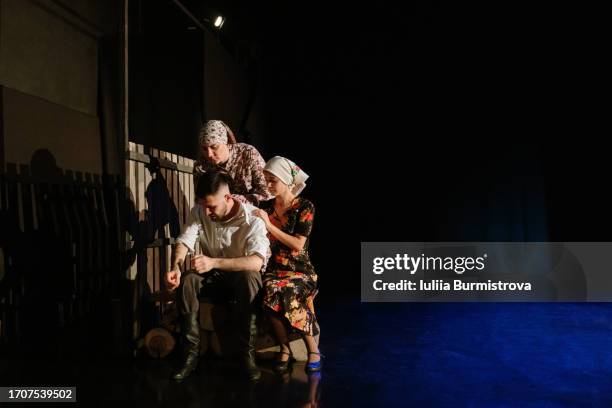 lone man sits with crestfallen expression while two compassionate women express comforting support during dramatic play at theater - community theater stock pictures, royalty-free photos & images