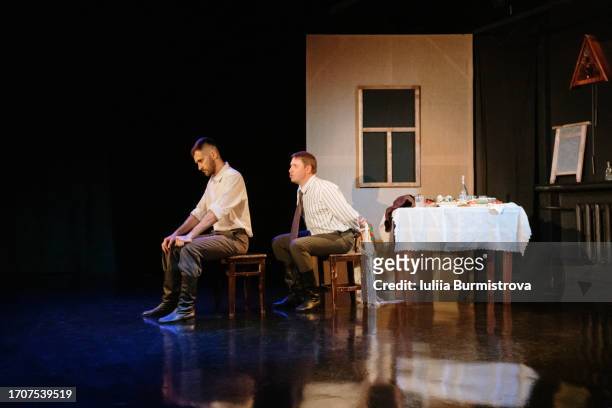 two men sitting on stage creating dramatic portrayal of male rivalry and tension during theater performance - 小道具 ストックフォトと画像
