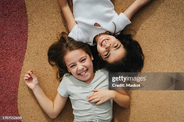 directly above view of happy sisters lying on footpath - supino foto e immagini stock