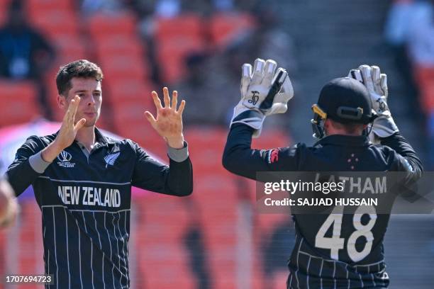 New Zealand's Mitchell Santner celebrates with his captain Tom Latham after taking the wicket of England's Jonny Bairstow during the 2023 ICC men's...