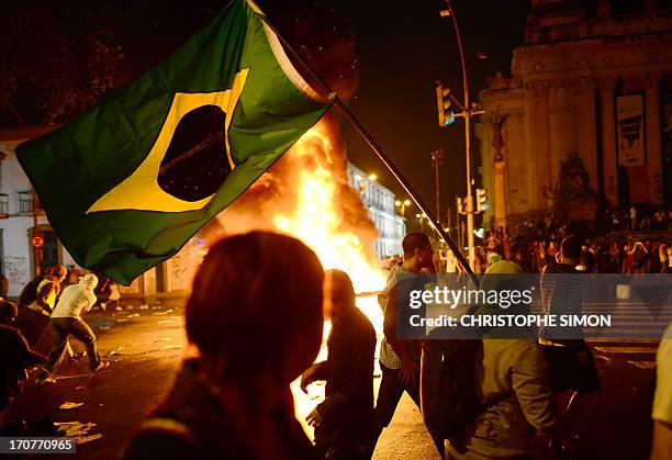 Demonstrator holds a Brazilian national flag during clashes in downtown Rio de Janeiro on June 17 after a protest against higher public...