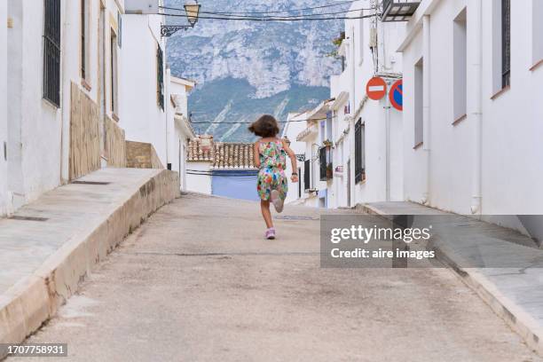 rear view of a tourist girl in casual clothes running in the streets with people in the background. - denia 個照片及圖片檔