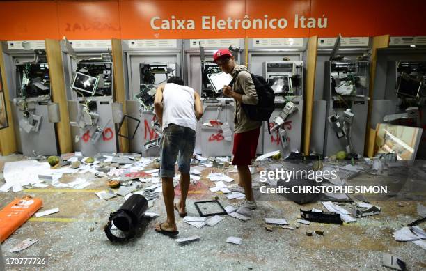Two men look at destroyed ATMs after vandals caused destruction during clashes in Rio de Janeiro's downtown, on June 17, 2013. Youths clashed with...