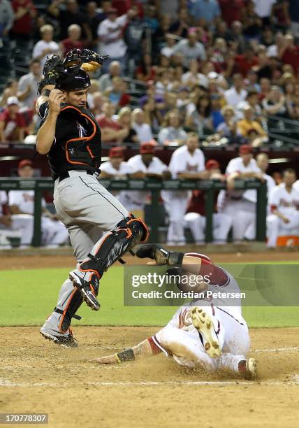 Gerardo Parra of the Arizona Diamondbacks safely slides under the tag from catcher Jeff Mathis of the Miami Marlins to score a run during the fifth...
