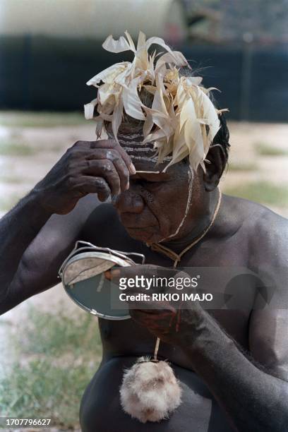 Photo taken on November 29, 1986 at the Blatherskite Park in Alice Springs shows an Aboriginal man painting his face holding a mirror as Pope John...