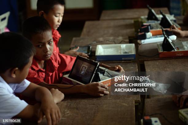 By Amélie BOTTOLLIER DEPOIS and Apilaporn VECHAKIJ This picture taken on May 27, 2013 shows a student using a tablet carrying a picture of king...