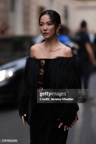 Yoyo Cao is seen outside Schiaparelli show wearing golden earrings, black hairy shoulder free Schiaparelli dress with golden button details during...