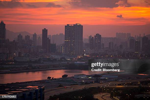 The sun sets over buildings in the Kowloon district of Hong Kong, China, on Wednesday, June 12, 2013. A shortage of housing, low mortgage costs and a...