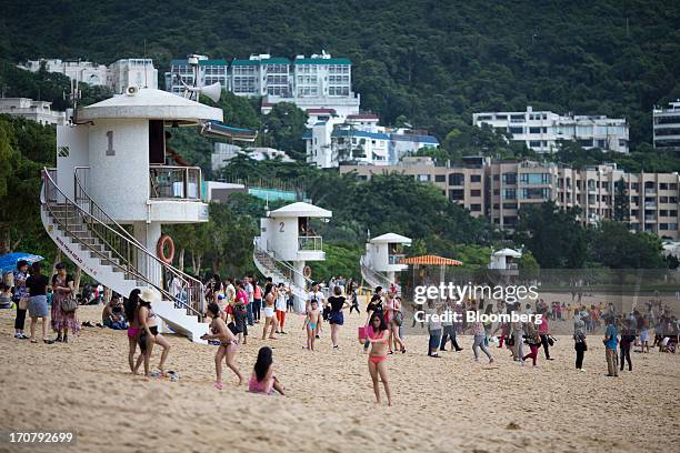 People gather at Repulse Bay beach in front of residential buildings in Hong Kong, China, on Sunday, June 16, 2013. A shortage of housing, low...