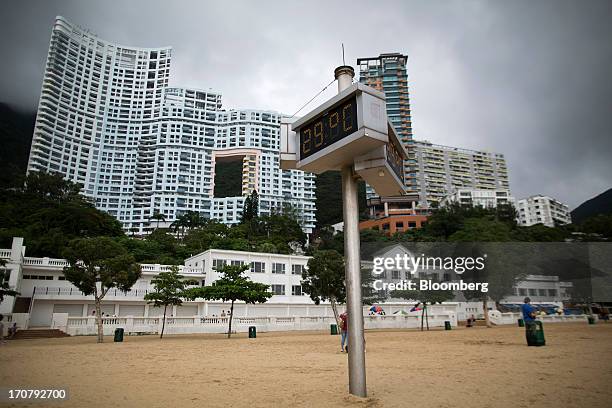 Residential buildings stand behind a temperature monitor at Repulse Bay beach in Hong Kong, China, on Sunday, June 16, 2013. A shortage of housing,...