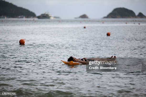 Woman lies on an inflatable float in the water at Repulse Bay beach in Hong Kong, China, on Sunday, June 16, 2013. A shortage of housing, low...