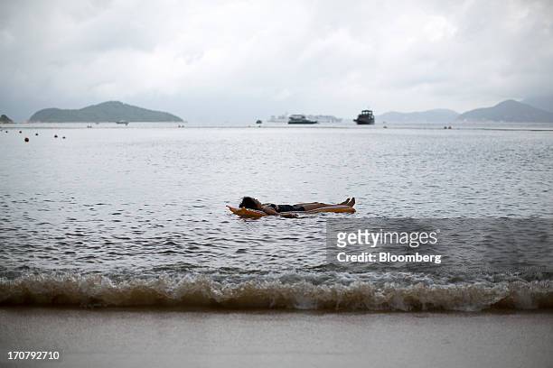 Woman lies on an inflatable float in the water at Repulse Bay beach in Hong Kong, China, on Sunday, June 16, 2013. A shortage of housing, low...