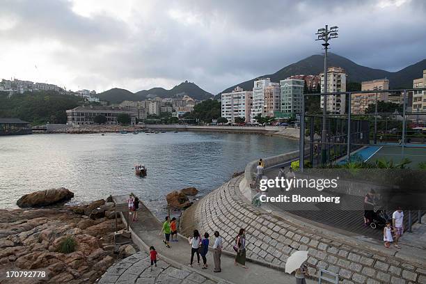 People walk along the waterfront across from residential buildings in the Stanley area of Hong Kong, China, on Sunday, June 16, 2013. A shortage of...