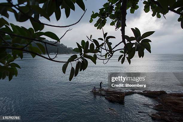 Two men fish on rocks on the waterfront in the Stanley area of Hong Kong, China, on Sunday, June 16, 2013. A shortage of housing, low mortgage costs...