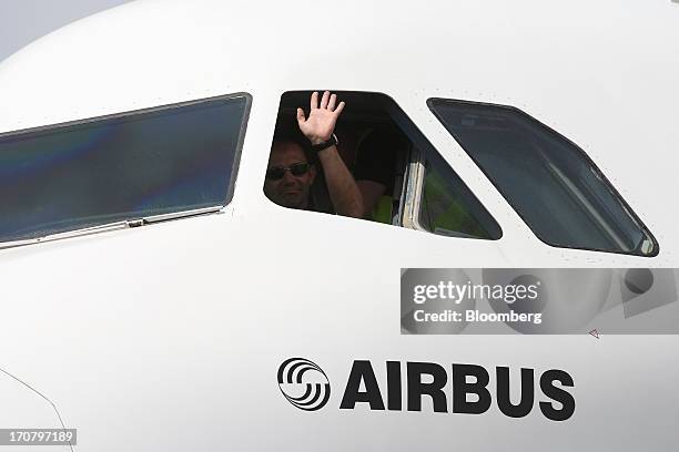 Pilot waves from the window of an Airbus SAS A320 aircraft as it moves across the tarmac on the second day of the Paris Air Show in Paris, France, on...