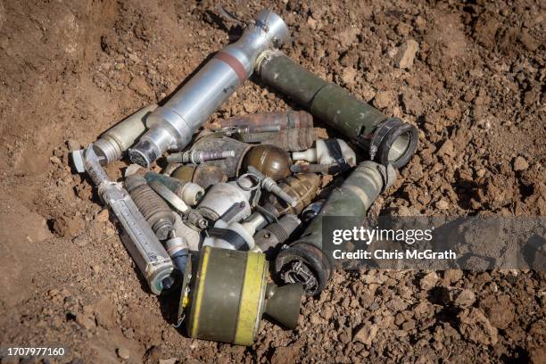 Member of a Ukrainian demining team places unexploded ordnance collected from across the region in a hole in an old crater from an airstrike ahead of...