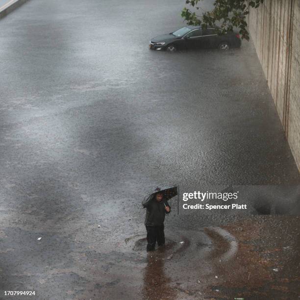 Person walks away from his vehicle after it got stuck in high water on the Prospect Expressway during heavy rain and flooding on September 29, 2023...