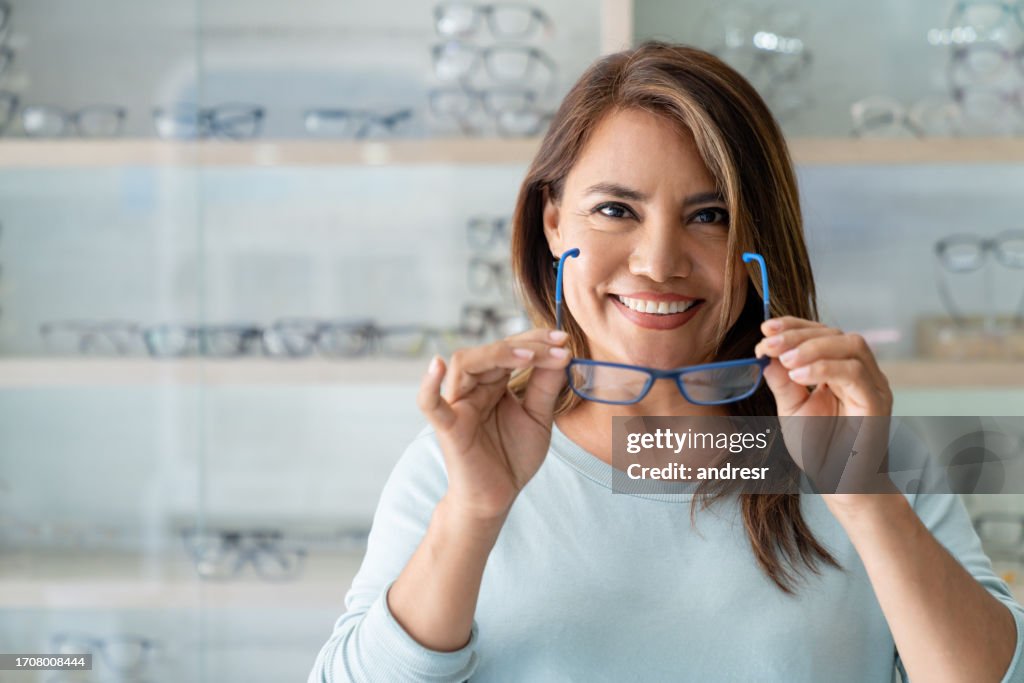 Happy woman trying on new glasses at the optician's shop