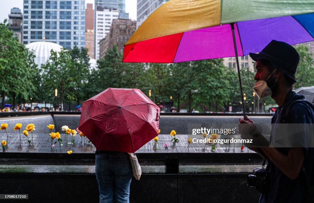 Pedestres usam guarda-chuvas para se abrigar da chuva enquanto caminham perto do marco zero no centro de Nova York