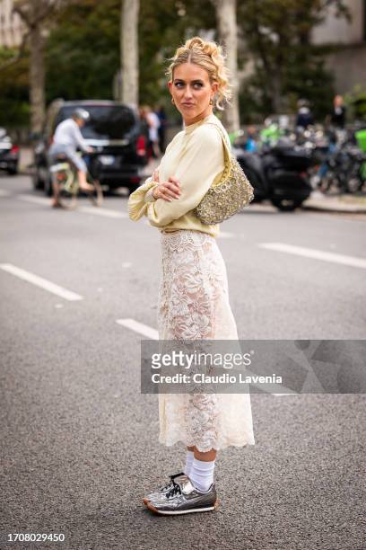 Emili Sindlev wears a yellow sweater, cream lace midi skirt, silver sneakers and yellow bag with silver metal details, outside Rabanne, during the...