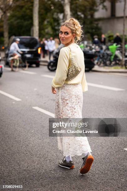 Emili Sindlev wears a yellow sweater, cream lace midi skirt, silver sneakers and yellow bag with silver metal details, outside Rabanne, during the...