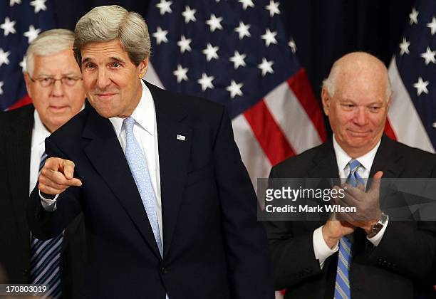 Secretary of State John Kerry , greets guests while flanked by Sen. Mike Enzi , and Sen. Ben Cardin after speaking during the 10th Anniversary...
