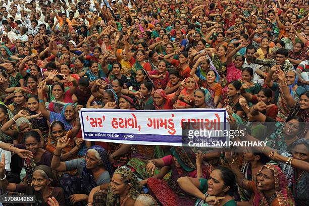 Indian farmers hold up a Gujarati language banner which reads "remove the Special Investment Region, save villages' during a rally in Gandhinagar,...