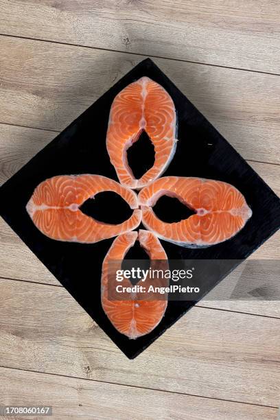 four slices of salmon arranged in a rhombus pattern on a slate plate. - aliment en portion stock pictures, royalty-free photos & images