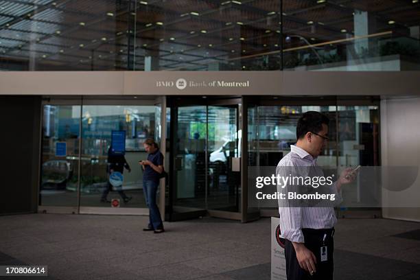 People check mobile phones in front of the Bank of Montreal in Toronto, Ontario, Canada, on Monday, June 17, 2013. The Canadian dollar declined for a...