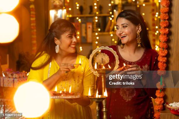 happy sisters lighting diyas at home during diwali - diwali stock pictures, royalty-free photos & images
