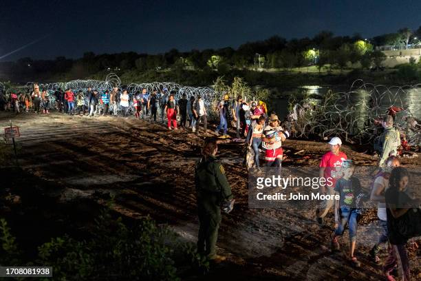Immigrants walk past razor wire after crossing the U.S.-Mexico border early on September 29, 2023 in Eagle Pass, Texas. A group of more than 500...