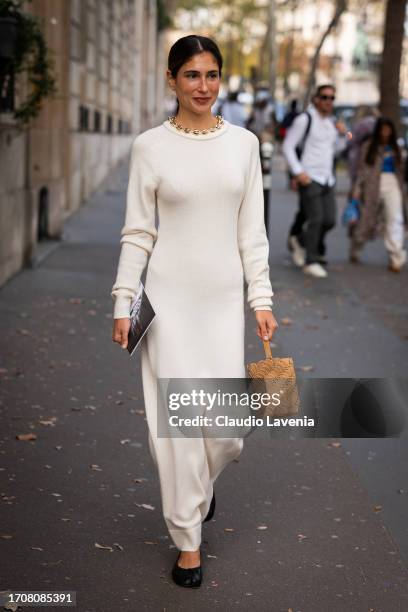 Belen Hostalet wears a cream knitted maxi dress, beige bag and black Maison Margiela tabi flat shoes , outside Rabanne, during the Womenswear...