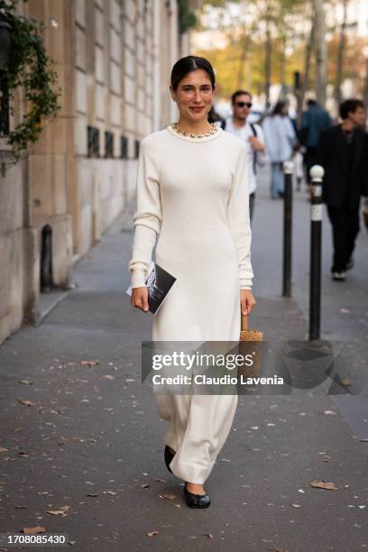 Belen Hostalet wears a cream knitted maxi dress, beige bag and black Maison Margiela tabi flat shoes , outside Rabanne, during the Womenswear...