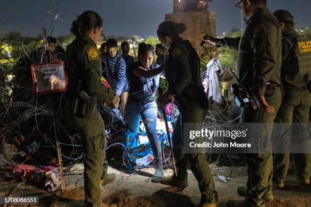 Border Patrol agents assist Venezuelan immigrant Argeiris Ramos to pass through razor wire at the U.S.-Mexico border on September 29, 2023 in Eagle...