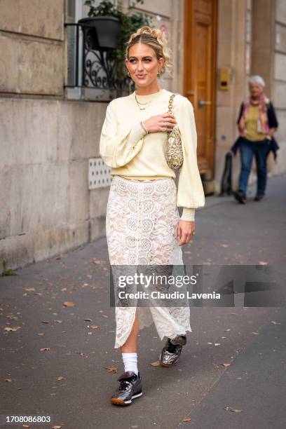 Emili Sindlev wears a yellow sweater, cream lace midi skirt, silver sneakers and yellow bag with silver metal details, outside Rabanne, during the...