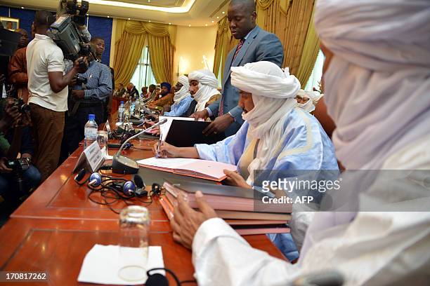 Alghabass Ag Intalla , leader of the Ansar Dine delegation, signs an agreement at a meeting on the Malian crisis on June 18, 2013 in Ouagadougou. The...