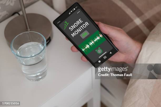 holding a smartphone with a snore monitoring app - thomas stock pictures, royalty-free photos & images