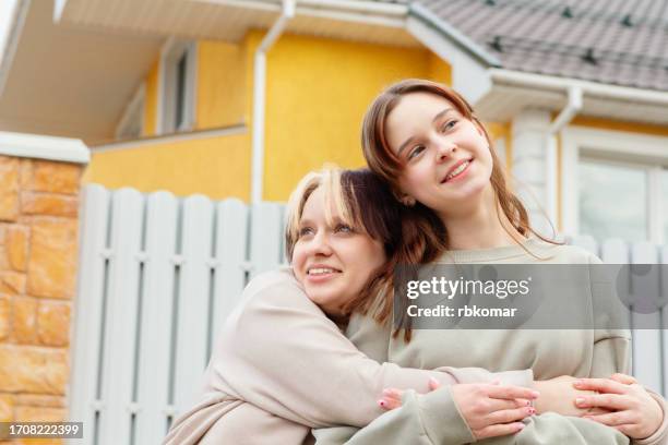 happy youth - beloved teen friends embracing in the yard near the house - teen lesbian stockfoto's en -beelden