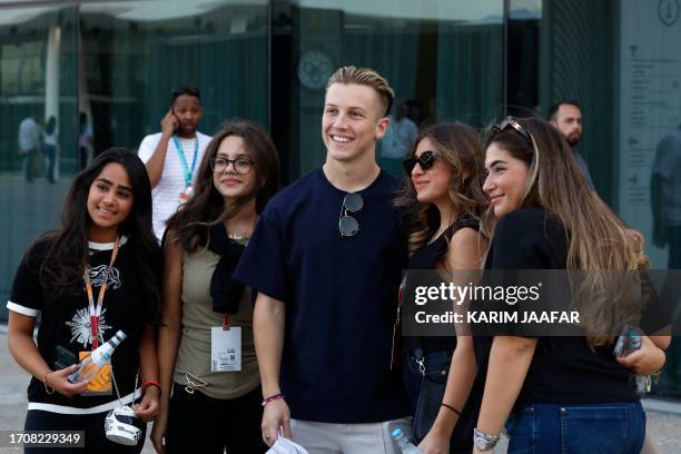 Alpha Tauri's New Zealander driver Liam Lawson poses for a picture with fans after arriving at the circuit ahead of the Formula One Qatar Grand Prix...