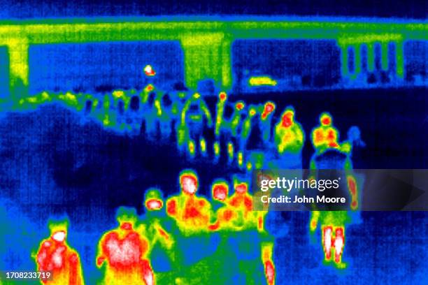 As seen with a thermal camera, asylum seekers line up near an international bridge to be processed by U.S. Border Patrol agents early on September...