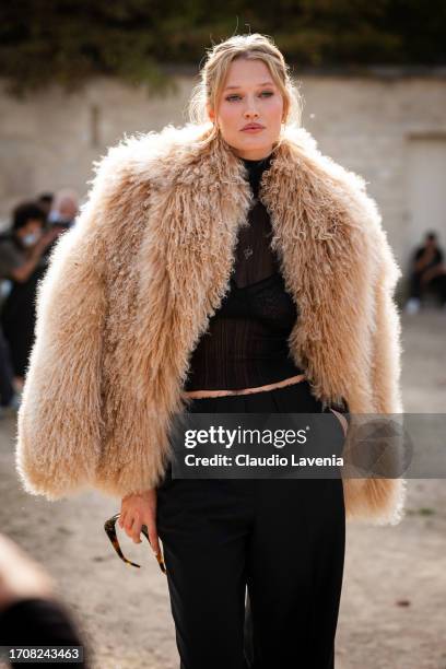 Toni Garrn wears a black sheer top, black trousers and nude fur jacket, outside Givenchy, during the Womenswear Spring/Summer 2024 as part of Paris...