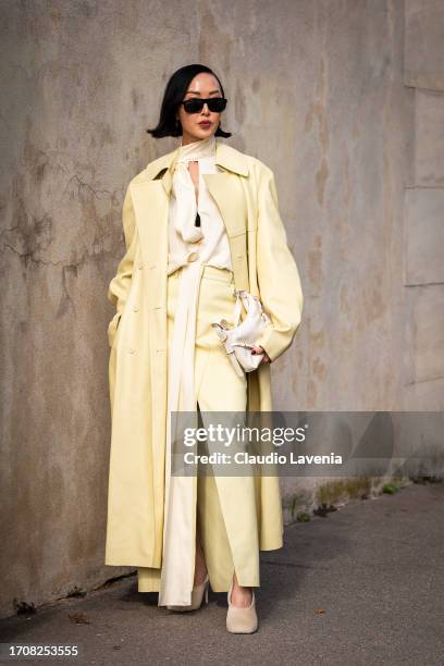 Chriselle Lim wears a light yellow blouse, yellow trousers, yellow leather long coat, beige heels and white Givenchy bag, outside Givenchy, during...