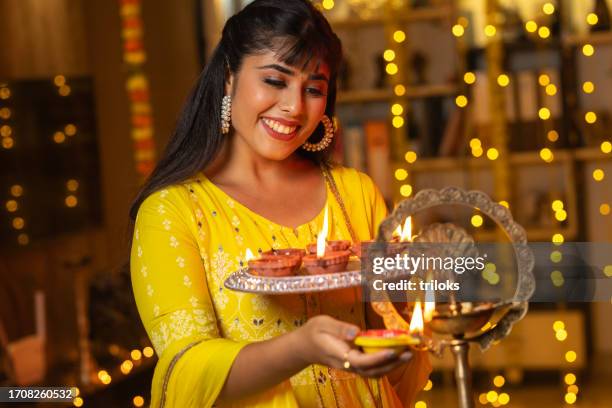 donna felice che accende diyas a casa durante diwali - bhai dooj festival celebration foto e immagini stock
