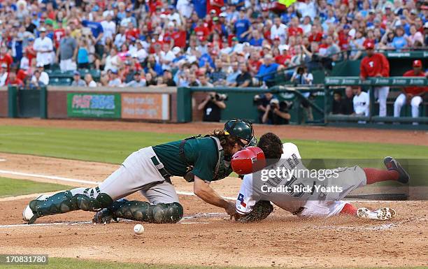 John Jaso of the Oakland Athletics drops the ball after colliding with Ian Kinsler of the Texas Rangers allowing Kinsler to score in the third inning...