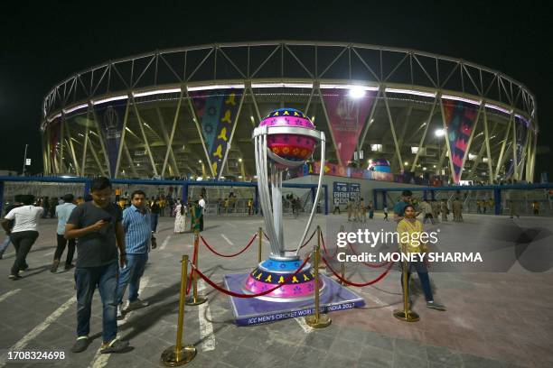 Spectators walk past a replica of ICC cricket World Cup trophy outside the Narendra Modi Stadium during the 2023 ICC men's cricket World Cup one-day...