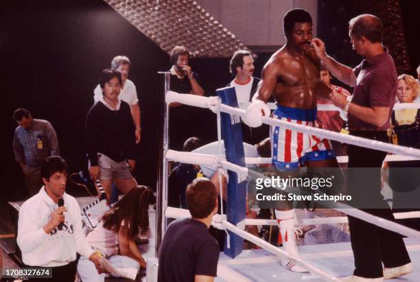 General view of cast and crew members in and around a boxing ring on the set of the film 'Rocky IV' , Los Angeles, California, 1984. Among those...